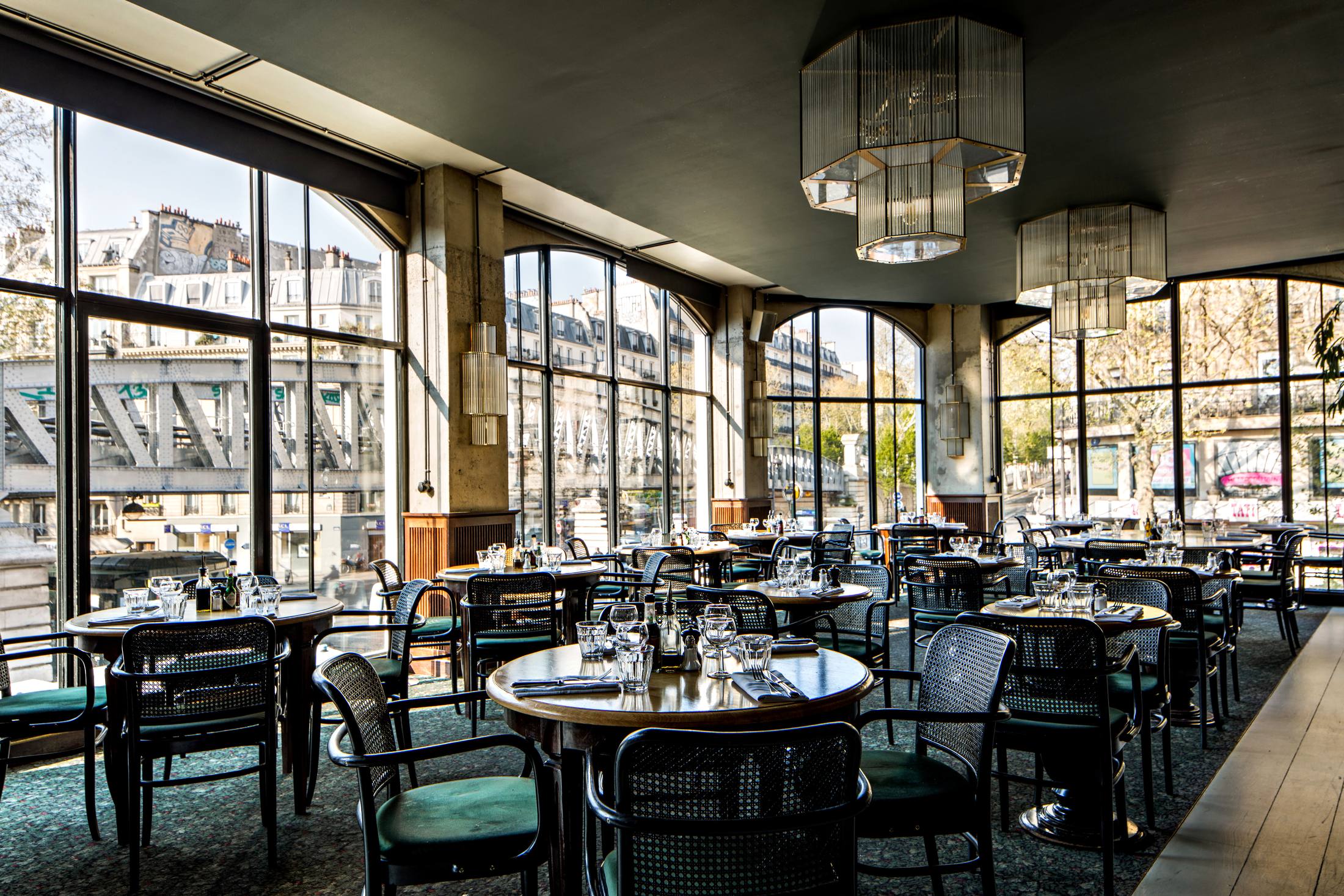 Le restaurant du premier étage de la Brasserie Barbès, ses verrières et ses tables dressées